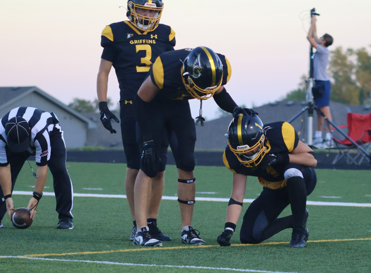 Taking a knee, senior Grayson Fisher is comforted by senior captains Joseph Costanzo and Carter Lightwine in the endzone after taking a hard hit in the last play of the Bennington game on Sept. 6.